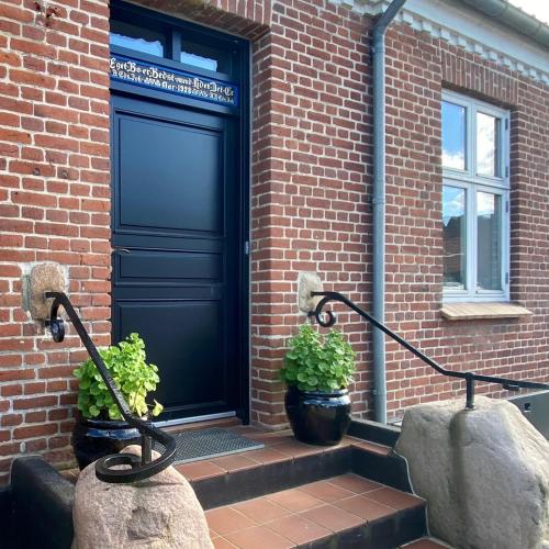 a blue door on a brick building with two plants at Birgittes B&B i Jelling in Jelling