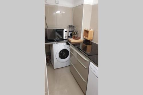une cuisine avec un lave-linge et un micro-ondes dans l'établissement Appartement front Vieux Port tout option jacuzzi, à Marseille