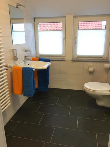 baño con lavabo, aseo y ventanas en Ferienwohnung „Im Kleinen Löök“ - DG - 2 Zimmer - Balkon - Boxspringbett - 2 TV, en Rinteln