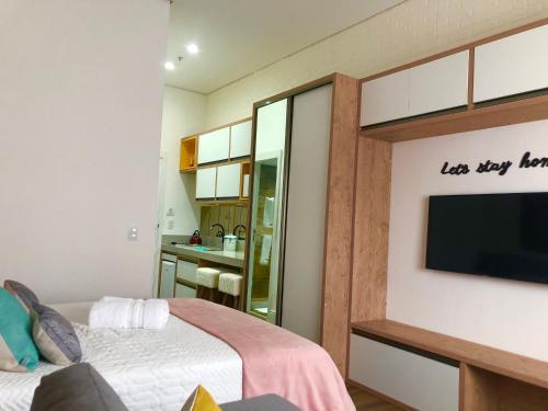 a bedroom with a bed and a flat screen tv at Lindo Loft Itaipava RJ in Itaipava