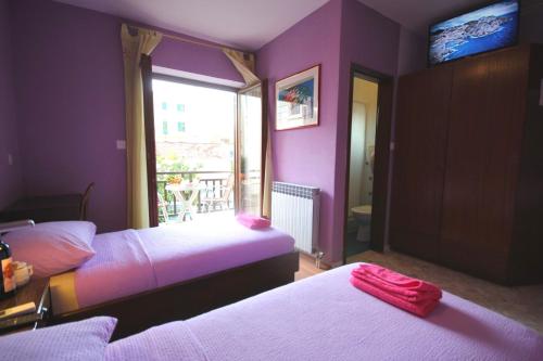 Dormitorio púrpura con 2 camas y ventana en Guest House Vila Micika Dubrovnik, en Dubrovnik