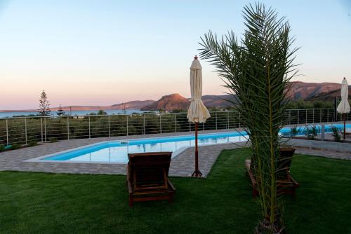a pool with a umbrella and two chairs and a palm tree at ONAR in Palekastron