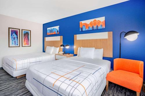 a hotel room with two beds and a chair at La Quinta Inn & Suites Katy-Mills by Wyndham Katy in Katy