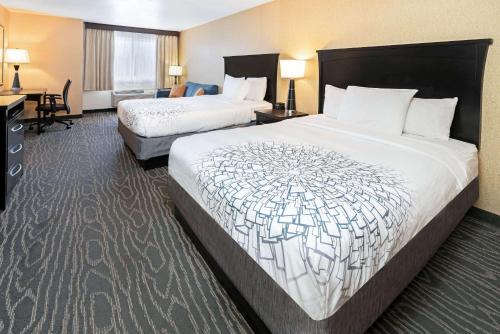 a hotel room with two beds and a desk at La Quinta by Wyndham Logan in Logan