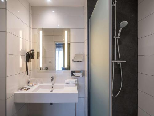 a bathroom with a shower, sink, and mirror at Mercure Bords de Loire Saumur in Saumur