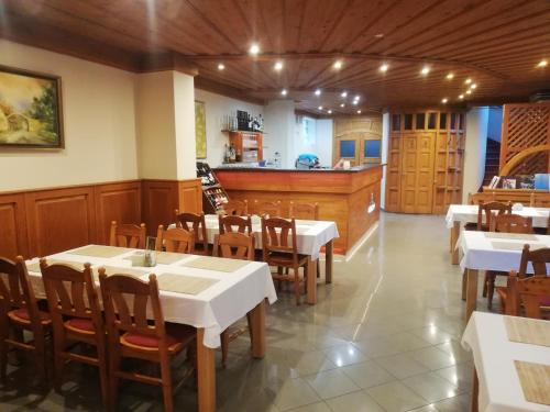 a restaurant with white tables and chairs and a counter at Levanda Panzió in Kópháza