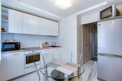 a kitchen with a glass table and white cabinets at Аппартаменты на Дзержинского,19 in Khabarovsk