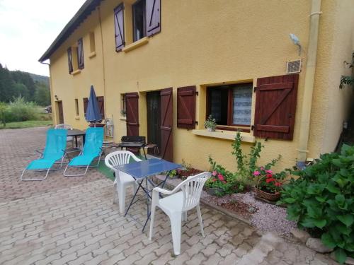 a patio with chairs and tables and a building at gîte des Hortensias in Raon-aux-Bois