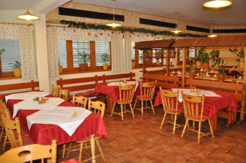 リュブリャナにあるPenzion Kmečki Hramの赤いテーブルクロスのテーブルと椅子が備わるレストラン