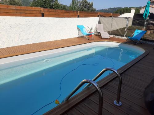 - une piscine sur une terrasse en bois avec des chaises dans l'établissement Maison avec piscine à l'orée de la forêt, à Vals-les-Bains