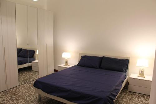 a bedroom with a bed with blue sheets and two lamps at Apartment Little Bari in Bari