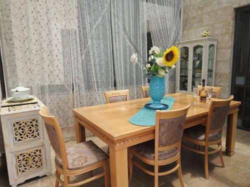 a dining room table with a vase of flowers on it at הים פוגש את ההר- בית בלב הגליל Sea & Mount in Adamit