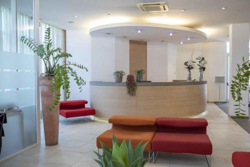 a lobby with a waiting area with red chairs at B&B HOTEL Remilia in Reggio Emilia