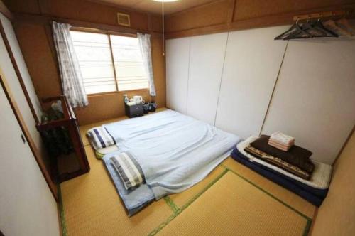 a small room with a bed and a window at Guest House Yamada in Date