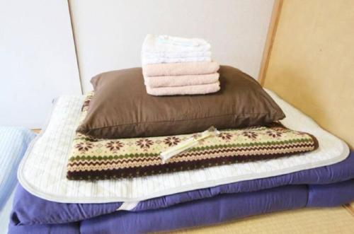 a bed with two pillows and towels on it at Guest House Yamada in Date