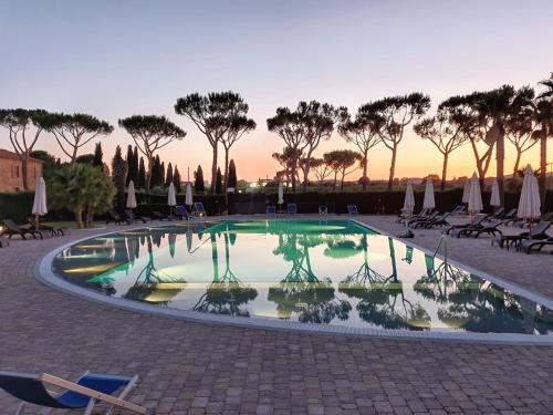 uma piscina com cadeiras e árvores e um pôr-do-sol em Agriturismo Cannavota em Follonica