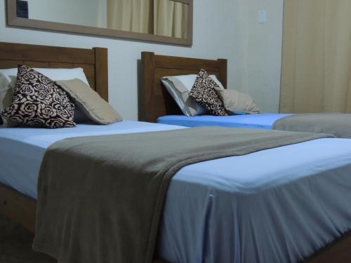 two beds with pillows and pillows in a room at Quartos Em Casa Caxias - Pousada Paraíso in Duque de Caxias