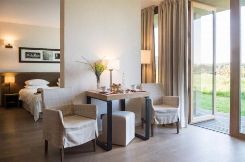 une chambre d'hôtel avec un lit, une table et des chaises dans l'établissement La Gree Des Landes - Eco-Hotel-Spa Yves Rocher, à Cournon