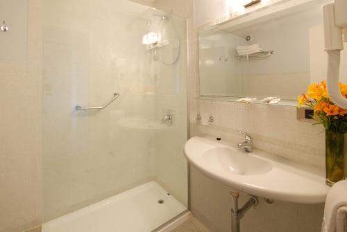 a white bathroom with a sink and a mirror at Hotel Tirol in San Carlos de Bariloche