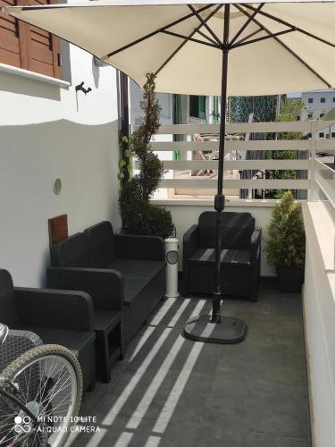 un patio con sillas y una sombrilla en el balcón en B&B Da Daniela en Magliano deʼ Marsi