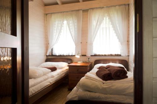 two beds in a room with two windows at Ośrodek Wczasowy Leśny Resort Mielno in Mielno