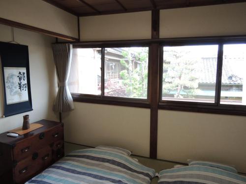 a bedroom with a bed and a dresser and windows at Kenroku House in Kanazawa