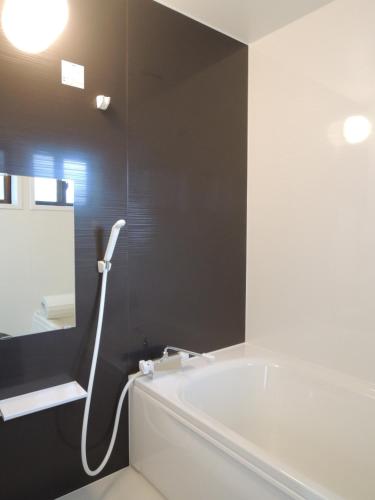 a bathroom with a white tub and a mirror at Kenroku House in Kanazawa