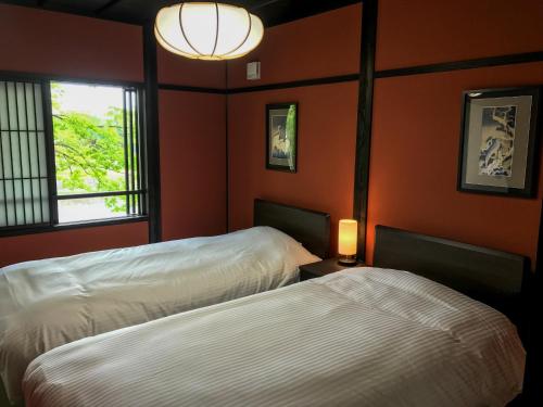 two beds in a room with orange walls at Saigawa House in Kanazawa