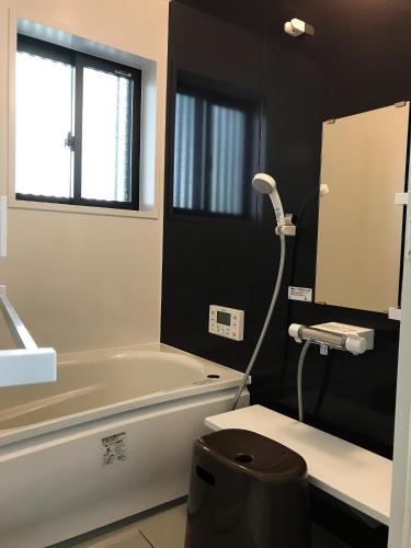 a bathroom with a tub and a sink and a mirror at Saigawa House in Kanazawa