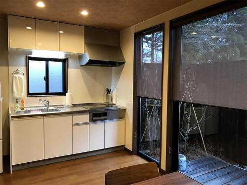 a kitchen with white cabinets and a sink and a window at Hida House in Takayama