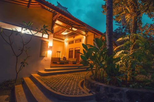 a house with palm trees in front of it at Adara Homestay in Banyuwangi