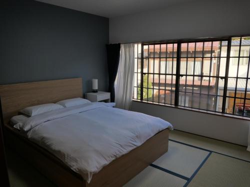 a bedroom with a large bed and a large window at Kanamori House in Takayama