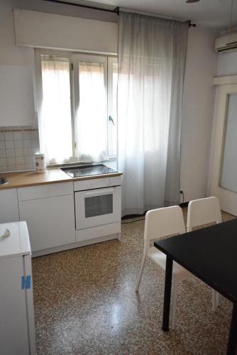 a kitchen with white cabinets and a table and chairs at Appartamento Paola in Mestre