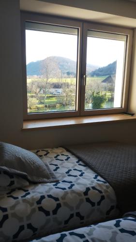 a bedroom with two windows with a bed and a view at Gite La Bastide in Ornans