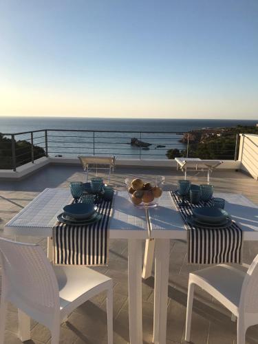 a white table and chairs with a view of the ocean at Cocciu d’amuri in Terrasini