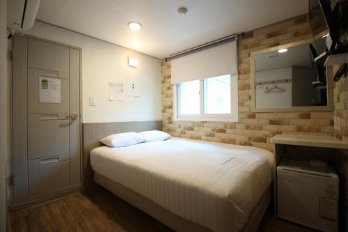 a small bedroom with a bed and a window at Dongdaemun Hwashin Hostel in Seoul