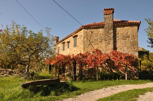 an old stone house with red trees in front of it at KIŽIN House, Cozy apartments by Istrian Embrace in Brezovica pri Gradinu
