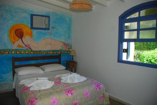 Schlafzimmer mit einem Bett mit Wandgemälde in der Unterkunft Pousada do Sidão in Ilhabela