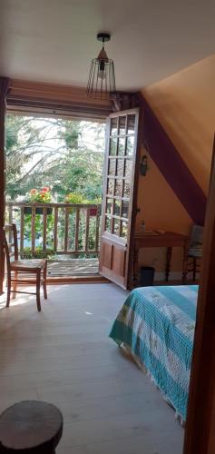 a bedroom with a bed and a sliding glass door at Chez Catherine - Chaumière Normande in Theuville-aux-Maillots