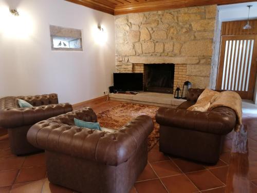 a living room with leather furniture and a stone fireplace at Casa Real in Barcelos