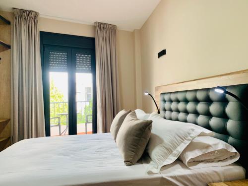 a bedroom with a bed with white pillows and a window at NerjaRooms in Nerja