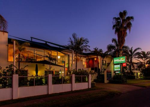 a building with a restaurant and palm trees at night at McNevins Maryborough Motel in Maryborough