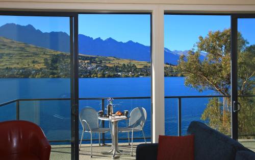 a room with a table and chairs and a view of a lake at Villa Del Lago in Queenstown