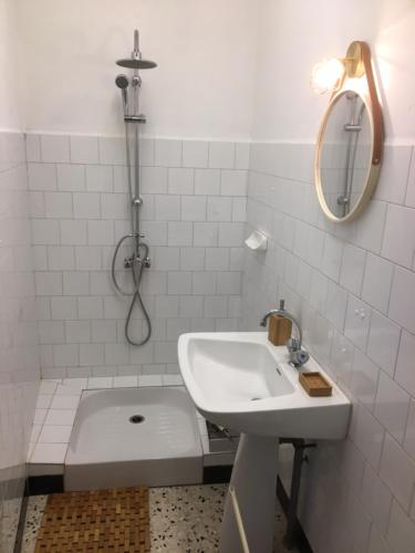 y baño blanco con lavabo y ducha. en Chez Tatie Ménie, en Fraissé-des-Corbières