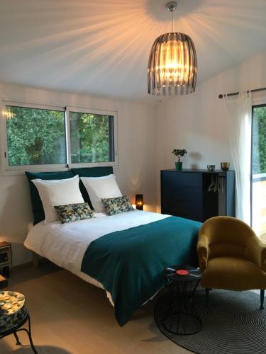 um quarto com uma cama, uma cadeira e um lustre em MADILOJE em Saint-Hilaire-de-Riez
