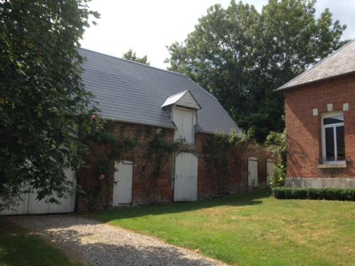 un edificio de ladrillo rojo con dos puertas blancas de garaje en GrIsa'Home le gîte, en Aisonville-et-Bernoville