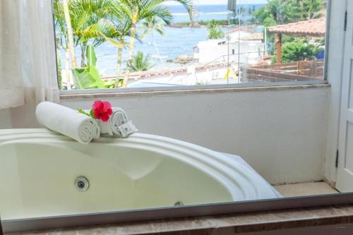 a white bath tub with a red flower on it at Pousada Ilha da Saudade in Morro de São Paulo