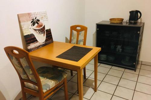 a wooden table with chairs and a picture of a coffee cup at Biete ruhige Zwei-Zimmer Souterrain-Wohnung in Niederkassel
