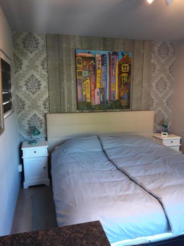 a bedroom with a bed and a painting on the wall at Celebration Wellnesshuisje in Balkbrug
