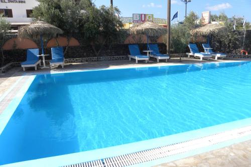 a large swimming pool with blue chairs and umbrellas at Petra Nera in Perissa